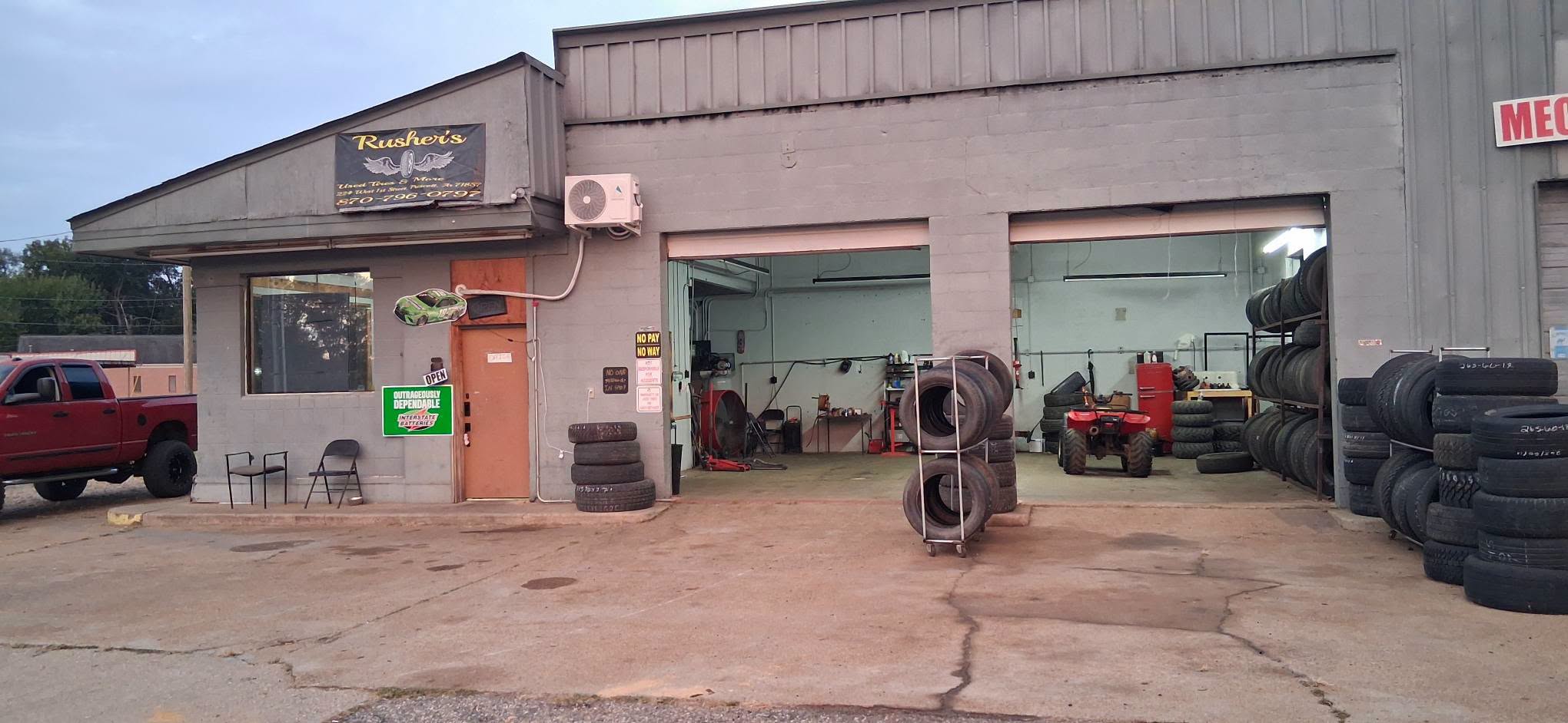 Rusher’s Used Tires & More storefront with open service bays and tire racks